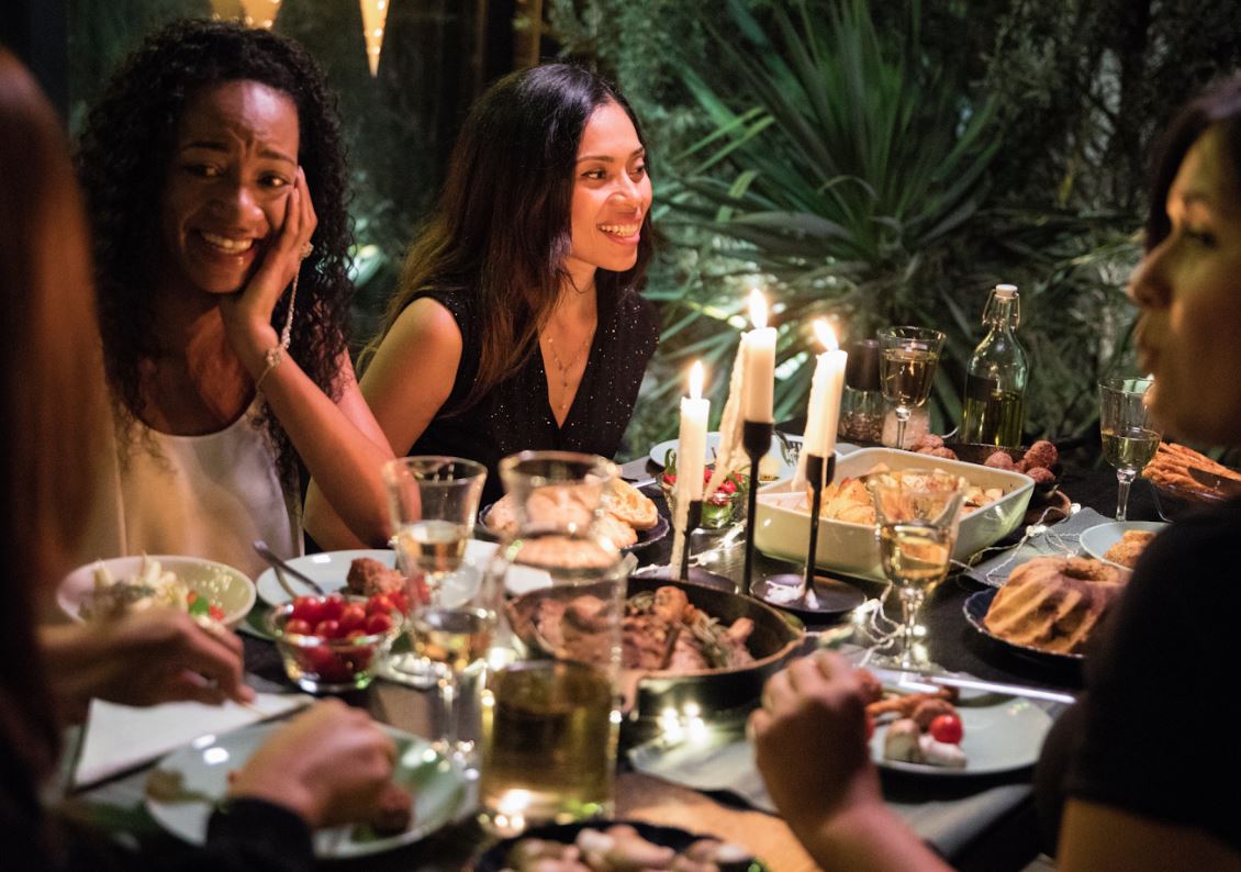 Guests sharing an evening dinner by candlelight, talking and laughing around the table
